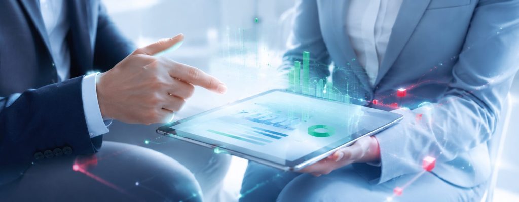 Zwei Personen in Anzügen betrachten Geschäftszahlen und Diagramme auf einem Tablet